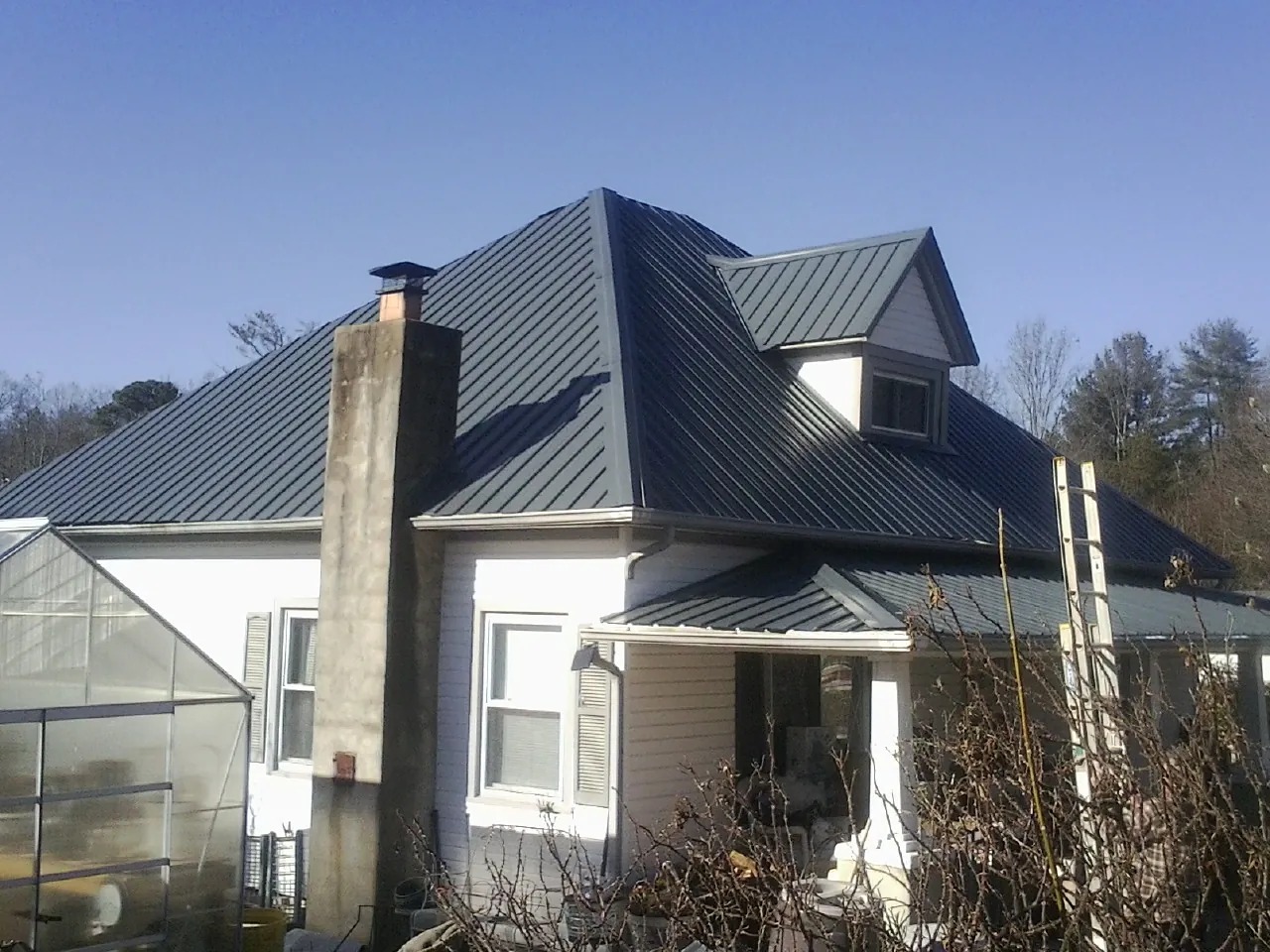 Dark blue standing seam metal roof on a white farmhouse with dormer — Slate & Tile Roof Repair by Roofing Brothers in Loomis