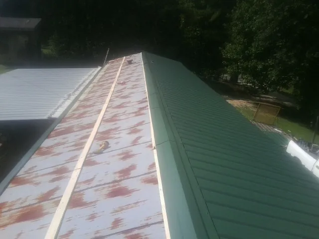 Old rusted panels beside newly installed green metal roofing — Wind Damage Roof Repair by Roofing Brothers in Loomis