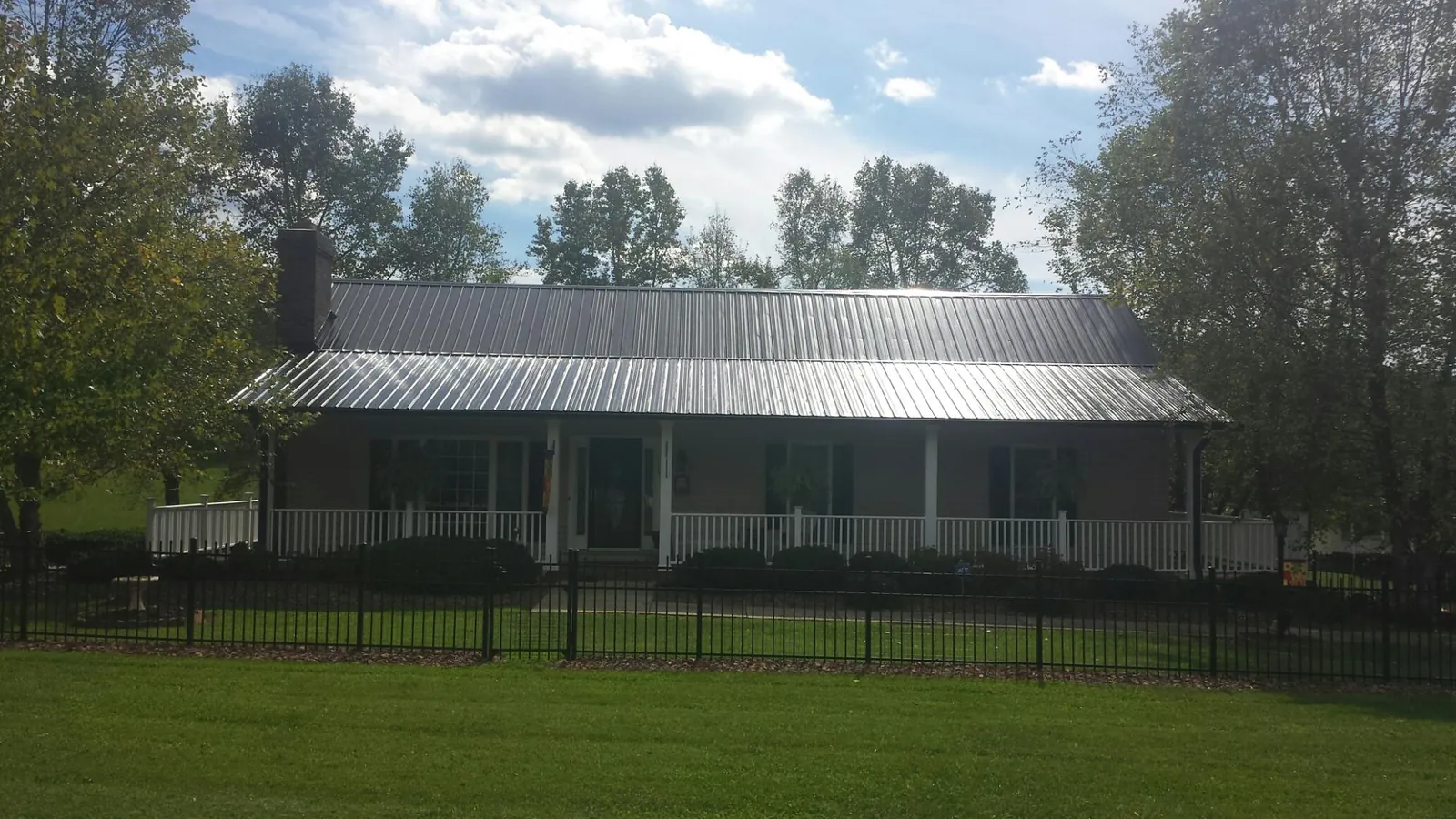 Gray metal roof on a brick ranch with a full width front porch — Gutter Guard Installation work by our crew in Loomis