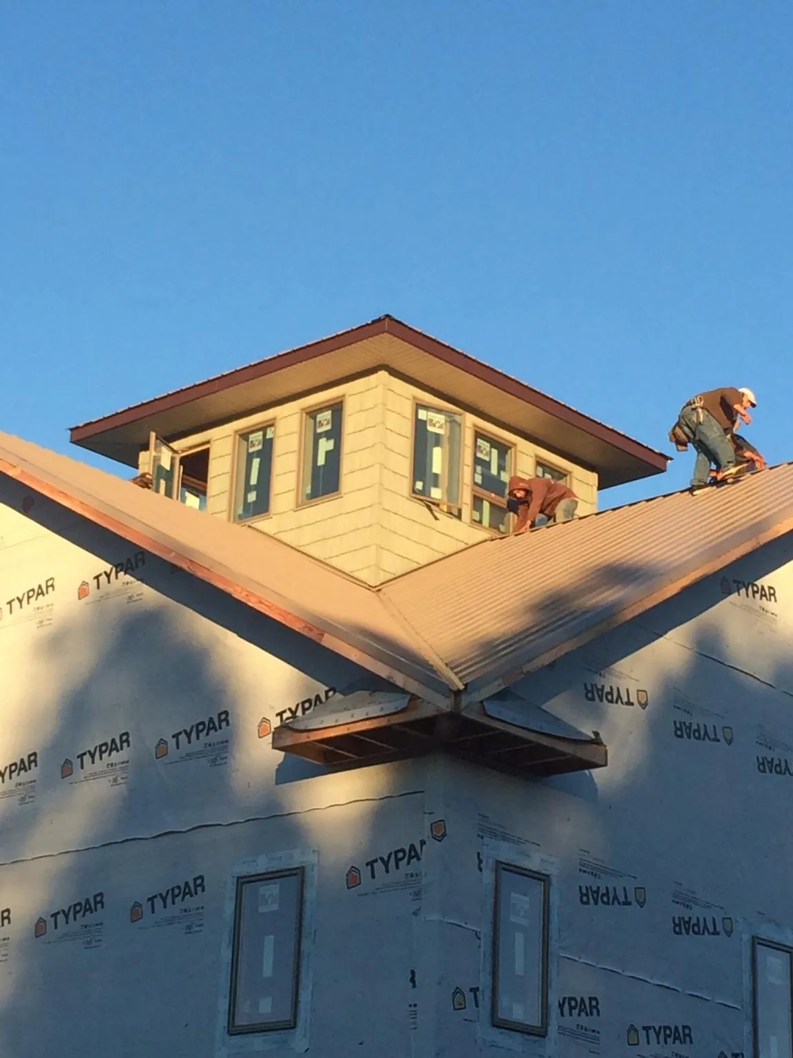 Roofers working around a rooftop cupola on a new metal roof at sunset — Roof Waterproofing in Loomis by Roofing Brothers